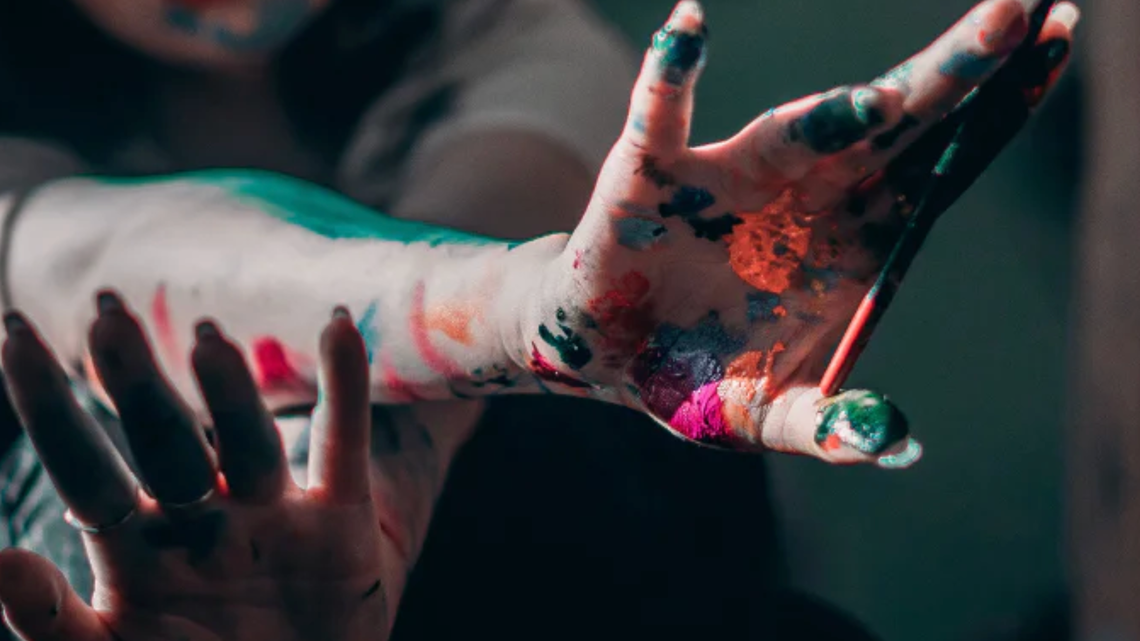 Girl holding paintbrush covered in paint