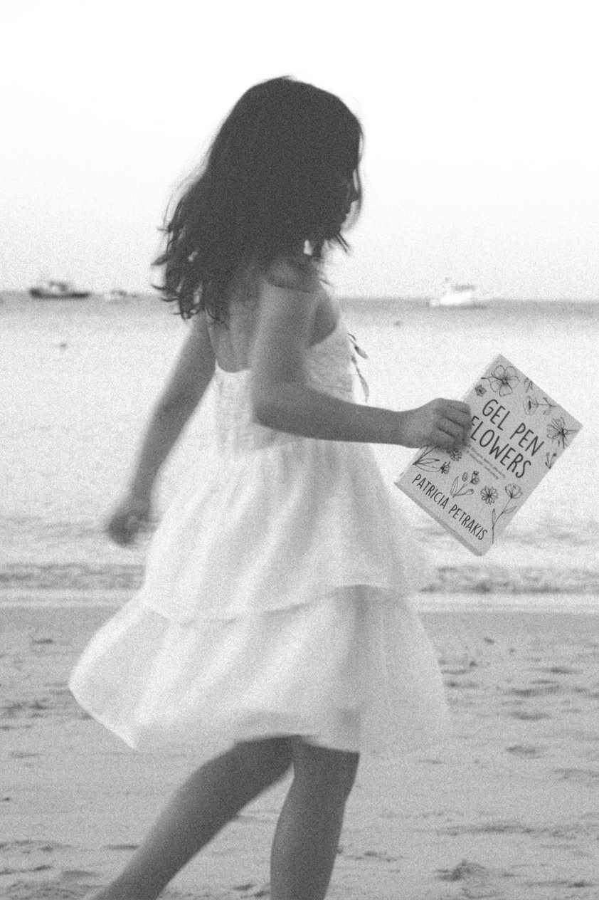 A younger version of Patricia holding Gel Pen Flowers on the beach, symbolizing creativity, memory, and reconnecting with her younger self